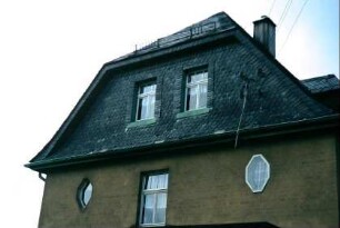Haus mit verschiefertem Giebeloberteil, darunter achteckige Fenster