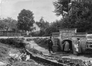 Zwei Frauen und ein Mann Wasser aus einem Brunnen holend