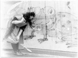 Als Prinzessin verkleidetes Mädchen beugt sich zu einem Graffiti eines Frosches herunter (Sonderthema: Traum-Bilder)
