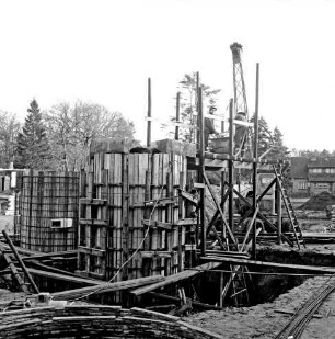 Abwasser: Klärwerk: Wöhrendamm: 3. Bauabschnitt: Bau des Belebungsbeckens, des Schlammstabilisierungsbeckens und des Nachklärbeckens: Baugrube und verschalte Beckenteile: rechts Gerüst: darauf Arbeiter: dahinter Bagger: hinten rechts Wohnhaus: im Hintergrund Bäume