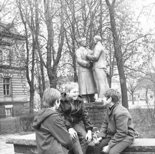 Denkmal am Stadthaus : Wurzen. Drei Jungen sitzen in einem Park vor einem sozialistischen Denkmal am Stadthaus
