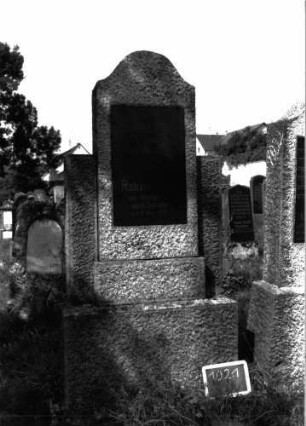 Grabstein 1021 (Index: 100104007) Material: Granit Zustand: gut erhalten Maße HxBxT: 193x83x25 cm Beschreibung: Stele auf getrepptem Sockel, Konvexbogenabschluss, halbhohe Seitenwangen, eingelassene hochrechteckige Schrifttafel: Grabstein 1021