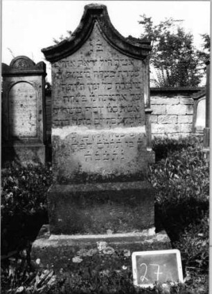 Grabstein 27 (Index: 99801887) Material: Sandstein Zustand: gebrochen und repariert mit Textverlust Maße HxBxT: 146x48x12 cm Beschreibung: Stele, getreppter Sockel, Kielbogenabschluß mit Verdachung: Grabstein 27