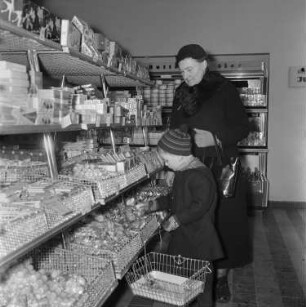 Dresden-Altstadt. Gewandhausstraße (1957-1958; H. Terpitz, G. Dettmar, H. Zimmermann). Lebensmittelladen "Hol fix". Kundin mit Kind beim Einkauf