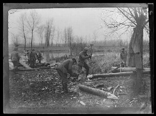 Soldaten an einem Gewässer beim Bearbeiten von Holz