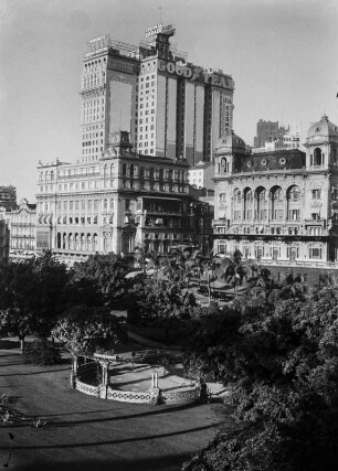 Hochhaus in São Paulo : Ein markantes Hochhaus in São Paulo mit Werbung für den Reifenhersteller "Good Year", eine Zahncreme und ein Bier. Im Vordergrund ein Park.