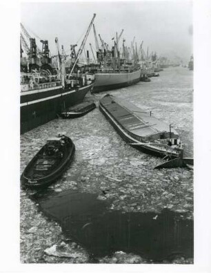 Hamburg. Der Hafen im Winter. Schlepper und Lastkähne bahnen sich ihren Weg durch das teileweise vereiste Hafenbecken