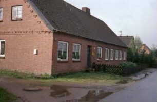 Alte Dorfstraße 1: ehemalige Gutsarbeiterkate, Mehrfamilienkate aus Backstein: traufständige Straßenfront mit Eingangstür: Giebelseite [angeschnitten]