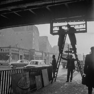 2 Männer auf Leiter putzen Leuchtanzeige, Bahnhof Friedrichstraße, 1970er Jahre. SW-Foto © Kurt Schwarz.