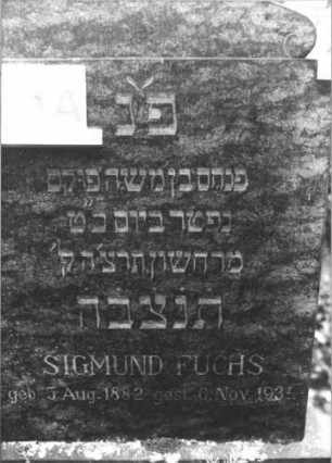 Grabstein 30 (Index: 100116480) Material: Granit Zustand: gut Maße HxBxT: 120x104x15 cm Beschreibung: Stele, breit, Sockel, giebelartiger Abschluß mit eingezogenen Voluten zu beiden Seiten Besonderheit: Doppelgrab, die zweite Beerdigung fehlt: Grabstein 30A