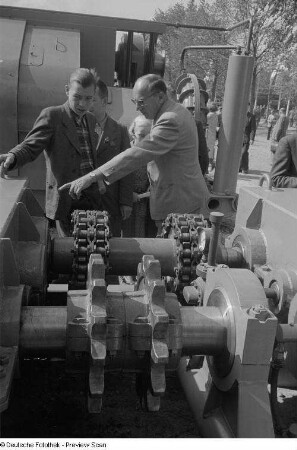 Besucher betrachten eine Maschine auf dem Freigelände der Technischen Messe 1953