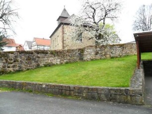 Heina-Evangelische Kirche - Ansicht von Osten mit Kirche über Kirchhofmauer (einst wehrhafe Kirchhofmauer - jetzige Höhe ein Viertel Original) in übersichtlichem Verlauf