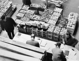 In einer Obst- und Gemüsehalle findet eine Auktion für Obst und Gemüse statt. Die Gebote werden entgegen genommen