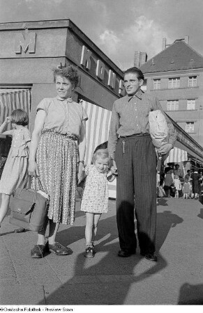 Familie mit Einkäufen vor einem Konsum