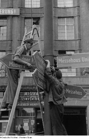 Arbeiter beim Anbringen von Hinweisschildern für die Herbstmesse 1953