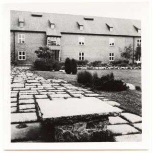 Grünflächen an der Albrecht-Dürer-Schule, Bromberg: Schulgebäude und im Vorgrund Steintisch