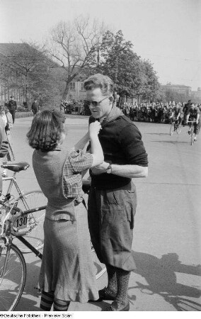 Radrennfahrer Gustav-Adolf Schur bekommt von einer Frau ein Halstuch umgebunden
