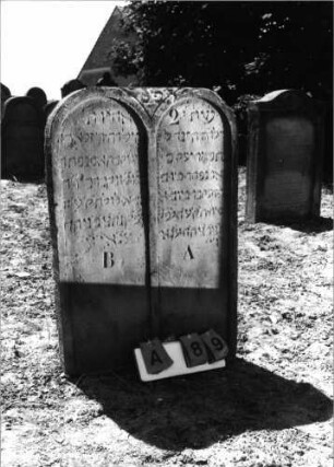 Grabstein 89 (Index: 99798152) Material: Sandstein, rot Zustand: leicht verwittert Maße HxBxT: 95x66x10 cm Beschreibung: Doppelstele, Rundbogenabschluß: Grabstein 89A