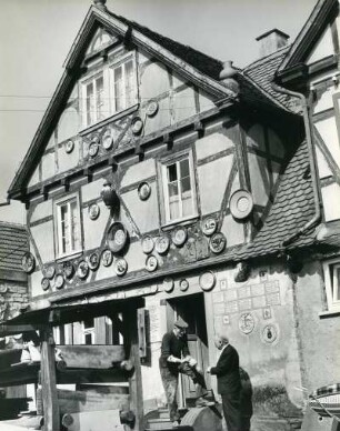 Bad Mergentheim im Main-Tauber-Kreis. Fassade einer Töpferei. Das alte Fachwerkhaus ist mit Keramikarbeiten verziert. Der Töpfermeister zeigt seine Erzeugnisse