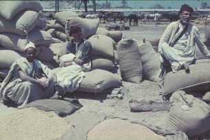 Reisefotos Libyen. Lastenträger vor gefüllten Säcken während einer Pause, Tripolis oder Bengasi?