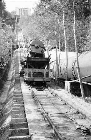 Häusern: Maschinenteil wird mit der Seilbahn [...], von unten