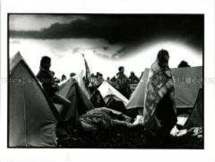 Die Fahne der USA inmitten von jungen, in Decken gehüllten Männern und wahllos aufgeschlagenen Zelten