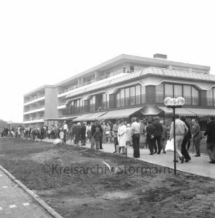 Seniorenwohnanlage Rosenhof I: Hoisdorfer Landstraße: Einweihung: Außenansicht des Gebäudekomplexes: davor Besucher mit Regenschirmen auf Weg