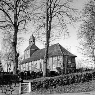 Evangelische Kirche: Blick von Südosten auf Apsis mit Kirchhof: vorn Hecke: links Gatter und Bäume