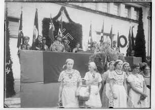 Erntedankfest in Sigmaringen 1935; Rednertribüne mit Redner am Mikrophon vor der Stadthalle; vorne in heller Uniform Kreisleiter Karl Maier; im Vordergrund Bäuerinnen; 3. von links: geb. Beuter; 2. von links: Westhauser