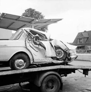 B 75: nach Verkehrsunfall bei Travenhof: Wrack von Unfall-Pkw auf Plattform von Abschleppwagen: auf Gelände von Tankstelle und Autowerkstatt "Stinnes": hinten rechts Geländer, Wohnhaus