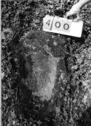 Grabstein 400 (Index: 99792062) Material: Sandstein Zustand: stark verwittert und abgeblättert mit großem Textverlust, Stele liegend Maße HxBxT: 80x48x15 cm Beschreibung: Stele, eingezogener Segmentbogenabschluß: Grabstein 400