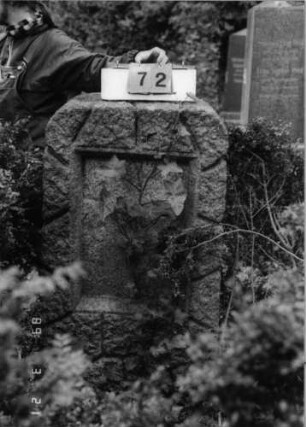 Grabstein 72 (Index: 99792580) Material: Granit Zustand: gut, Schriftplatte fehlt Maße HxBxT: 135x66x35 cm Beschreibung: Stele, rustica, Korbbogenabschluß, rechteckiges Schriftfeld eingetieft: Grabstein 72