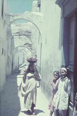 Reisefotos. Libyen. Tripolis. Straßenbild (jüdisches Viertel) mit drei Kindern (ein Mädchen, eine Schale auf dem Kopf tragend)