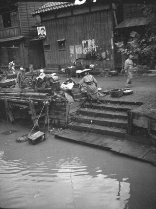 Niigata. Straße an einem Kanal : Niigata. Straße an einem Kanal. Ansicht mit Straßenhändlerin am Treppenaufgang einer Bootsanlegestelle