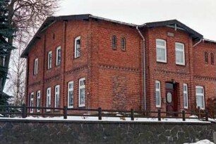Langniendorf: Hauptstraße 49: traufständiges Bauernhaus aus Backstein: Teilansicht: Giebelseite Wohntrakt: Straßenfront Wohntrakt mit Eingangsrisalit, Tür: im Vordergrund Feldsteinmauer, Zaun