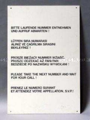 Schild "Bitte laufende Nummer entnehmen und Aufruf abwarten!" aus dem Arbeitsamt Berlin-Kreuzberg (5-sprachig)