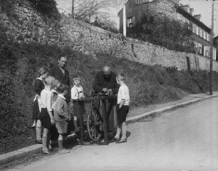 Mann und Kindergruppe um einen Messerschleifer : Sachsen. Unbekannter Ort. Straßenszene mit Mann und Kindergruppe um einen Messerschleifer