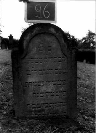 Grabstein 96 (Index: 100107253) Material: Sandstein Zustand: leicht verwittert, eingesunken Maße HxBxT: 82x52x12 cm Beschreibung: Stele, eingezogener Rundbogenabschluß: Grabstein 96