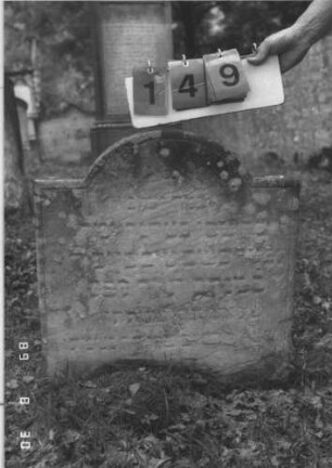 Grabstein 149 (Index: 99609785) Material: Sandstein Zustand: stark verwittert, abblätternd Maße HxBxT: 64x62x10 cm Beschreibung: Stele, eingezogener Segmentbogenabschluß, Schriftfeld eingetieft: Grabstein 149