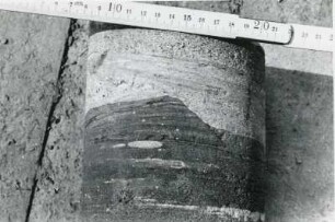 Freital-Zauckerode. Paul-Berndt-Grube (ehemaliger Königin-Carola-Schacht). Tiefbohrung F (Freital) 7, Teufe (Tiefe im Bergwerk) 143,30 m. Bohrkern (133 mm Durchmesser) aus grauen Sandstein mit Kreuzschichtung (oben) und braunrötlichen Tonsteinen und Konglomerat. Ausschnitt. Beispiel für Erosion