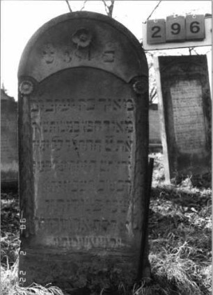 Grabstein 296 (Index: 100115885) Material: Sandstein Zustand: verwittert mit Textverlust Maße HxBxT: 128x61x12 cm Beschreibung: Stele mit Rundbogenabschluß, eingetieftes Schriftfeld mit eingezogenem Segmentbogenabschluß Symbolik: Blüten, Ranken: Grabstein 296