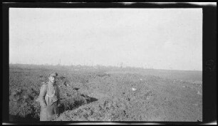 A.O.K.-Stellung an der Somme (Fluss im Norden Frankreichs): Leutnant Maily mit über der Brust geschnalltem Tornister bis zu den Oberschenkeln in einem Laufgraben stehend, dahinter Blick auf Sailly-Saillisel (Dep. Somme, Frankreich)