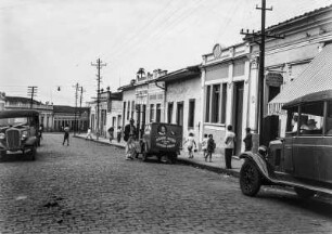 Belebte Straße : Eine gepflasterte Straße in Limeira mit geparkten Fahrzeugen am Straßenrand und zahlreichen Passanten auf dem Gehweg.