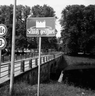Schlossbrücke: mit Gittertor: im Vordergrund Hinweisschild "Schloß geöffnet", Lampenmast, Verkehrsschilder: Schlossgraben: hinten Schlossinsel