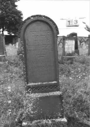 Grabstein 13 (Index: 100108065) Material: roter Sandstein Zustand: angeschlagen und abblätternd Maße HxBxT: 163x52x51 cm Beschreibung: Stele mit Rundbogenabschluß, getreppter Sockel Symbolik: Zickzack- und Kreuzmuster: Grabstein 13