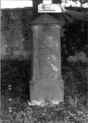 Grabstein 441 (Index: 100107971) Material: roter Sandstein Zustand: versalzen Maße HxBxT: 149x46x27 cm Beschreibung: Stele mit Giebelaufsatz, Seitenkanten stark abgephast, Sockel: Grabstein 441