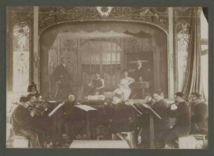 Theatervorstellung im Kriegsgefangenenlager Ludwigsburg-Eglosheim in Jugendstil-Kulissen, vier Schauspieler auf Bühne, davor Orchester