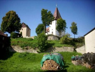 Ansicht von Südosten mit Kirche in erhöht liegendem Kirchhof am (ehemaligen) Ortsrand-einst zwei Kirchhofmauern (innere höher mit Wehrgang sowie äußere Zwingermauer)