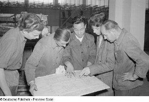 Fünf Personen studieren eine technische Zeichnung beim Aufbau des chinesischen Pavillons für die Herbstmesse 1953
