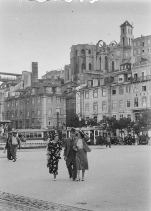 Praça de D. Pedro IV. : Ein Mann und zwei Frauen auf der Praça de D. Pedro IV. Im Hintergrund die Ruine der Klosterkirche des Convento do Carmo. Links am Bildrand die Brücke zum Aufzug Elevador de Santa Justa.